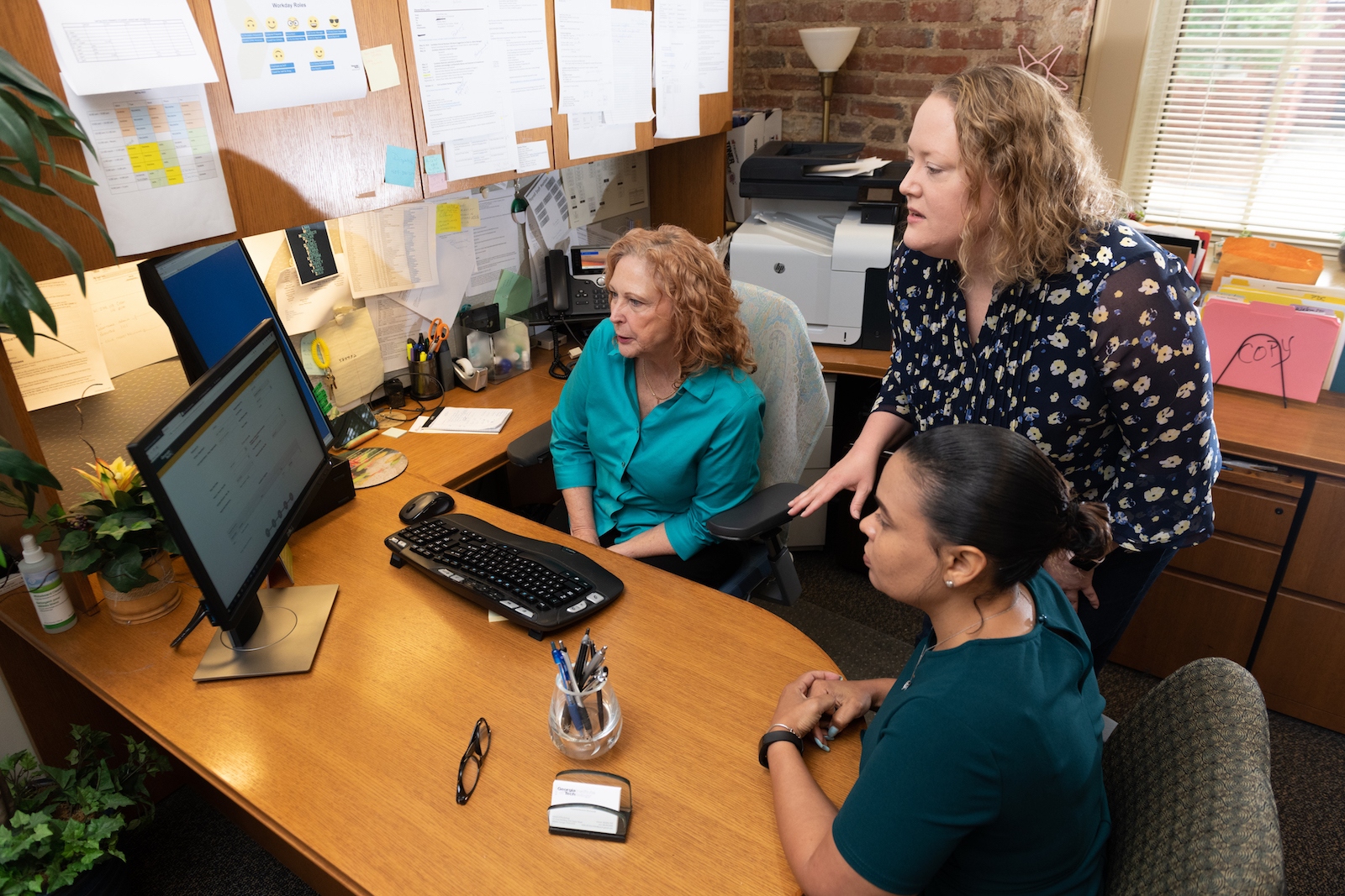 Erin Nagle (standing) discuss PROMOTE software with the School of Psychology's Leslie Dionne-White (left) and Kristie Clark.