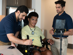 Kinemo co-founders Nordine Sebkhi and Arpan Bhavsar work with Wendell Odom during an assistive technology session using the Kinemo device to support independent computer and device control.
